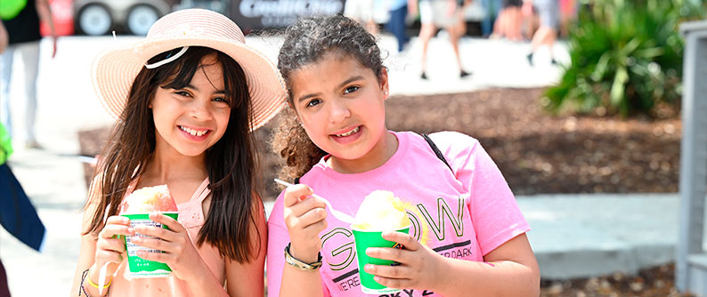Two kids smiling as they eat snow cones. 